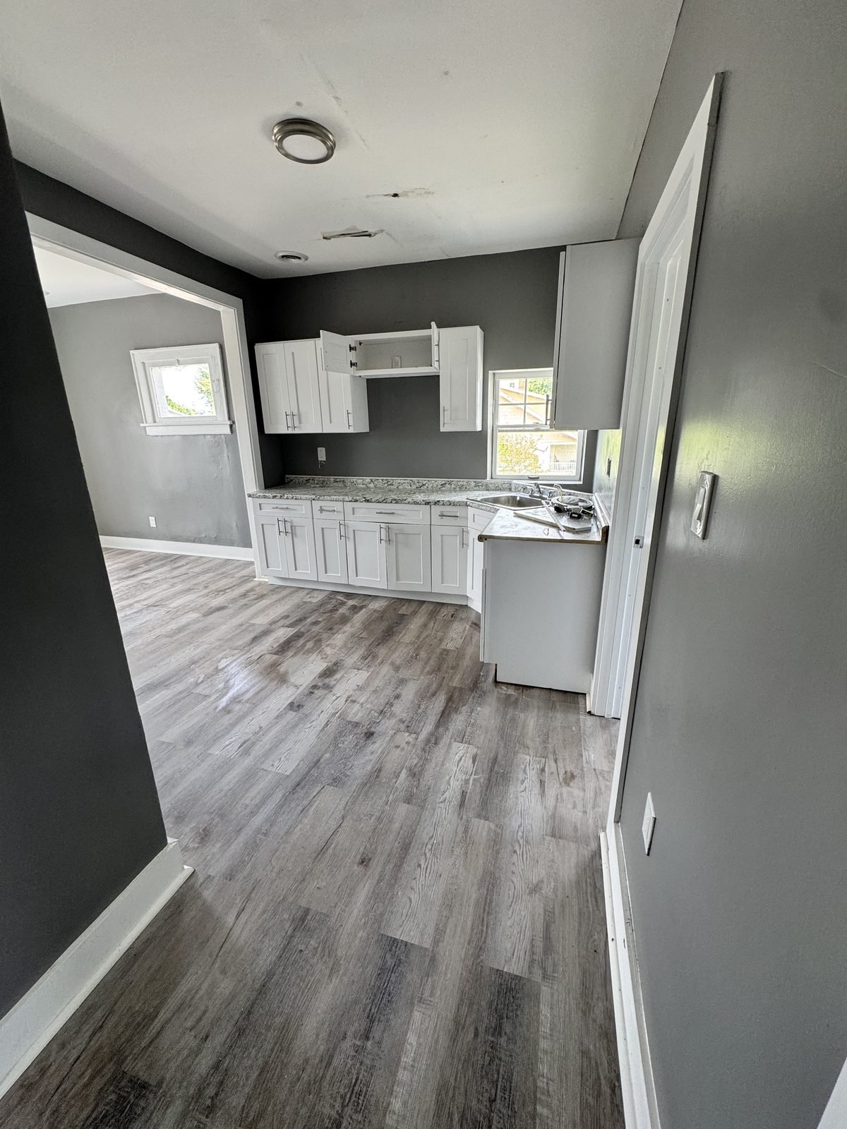 Kitchen after: new white cabinets, plank flooring, fresh paint